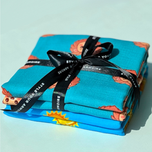 Two folded organic muslin swaddles with high contrast sun and lion prints.