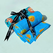 Two rolled organic muslin swaddles, one with sun print and with a lion print. 